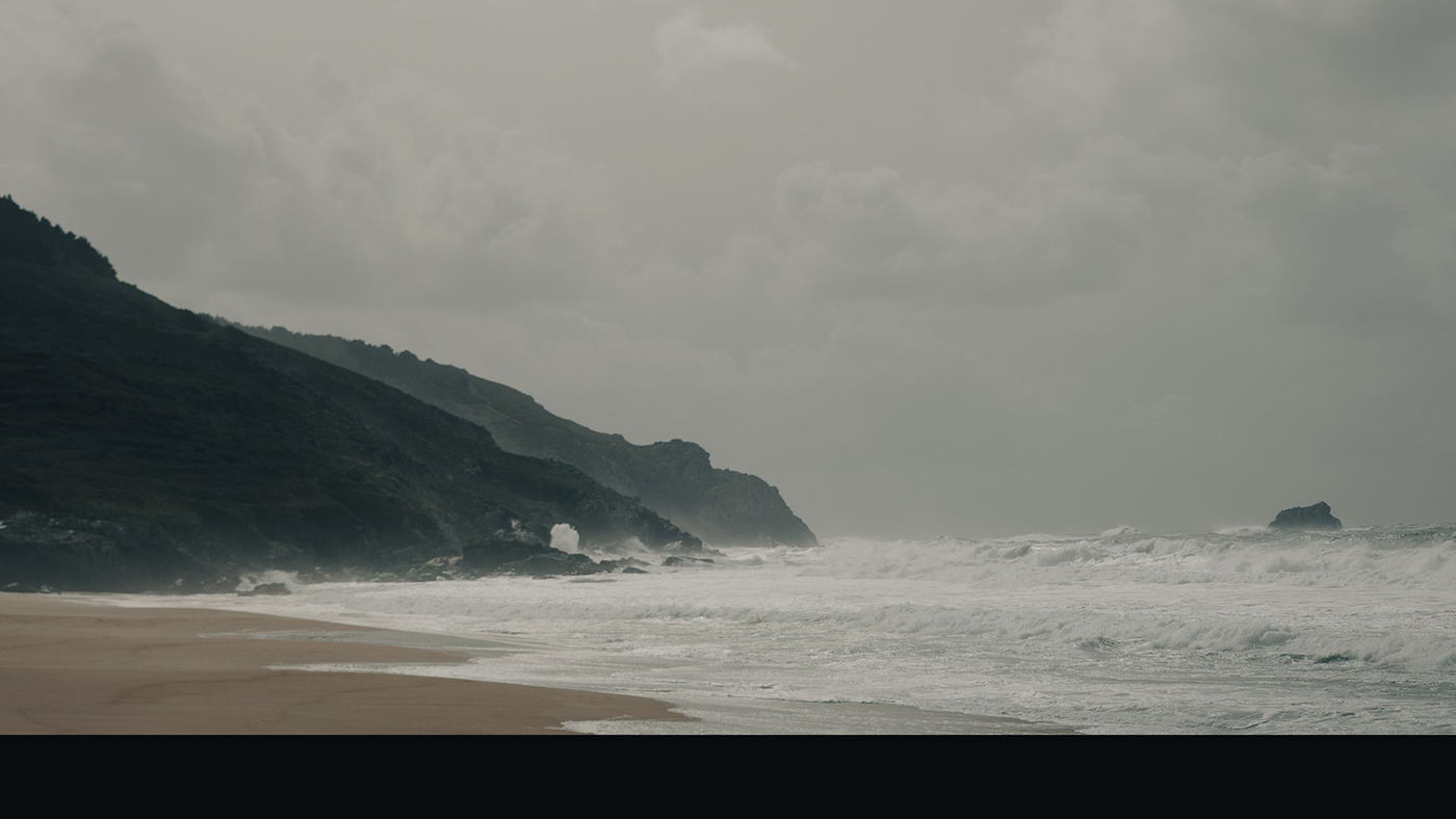 A praia e o mar coas ondas batendo nos cantís